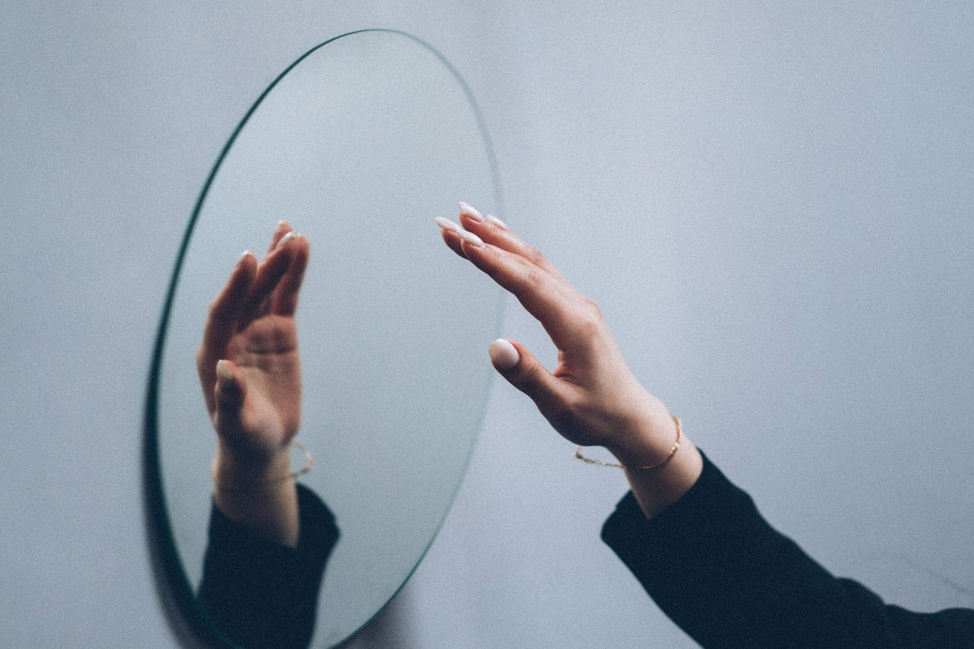 Eine Hand vor einem Spiegel un die Hand als Spiegelbild